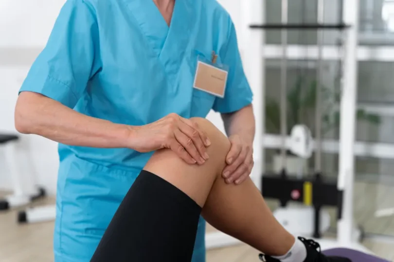 Ein Physiotherapeut untersucht das Knie eines Patienten während einer Rehabilitations- oder Therapiesitzung in einer Praxis.