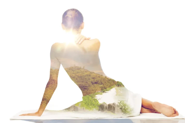 Doppelte Belichtung: Eine Frau sitzt mit dem Rücken zur Kamera, ein Handtuch um die Hüften gewickelt. In ihrem Oberkörper spiegelt sich eine Naturkulisse mit grünen Hügeln und einem sandigen Küstenstreifen, symbolisierend für Harmonie zwischen Körper und Natur.