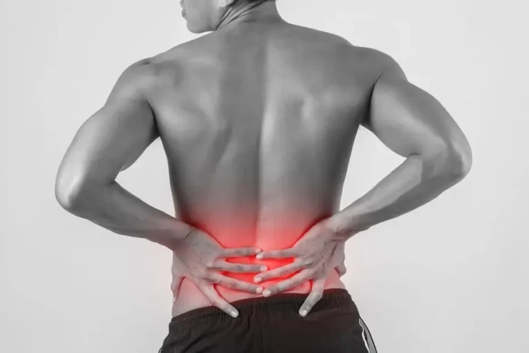 Mann hält sich mit beiden Händen den schmerzenden unteren Rücken – symbolisch für Beschwerden bei einem Bandscheibenvorfall im Lendenbereich.