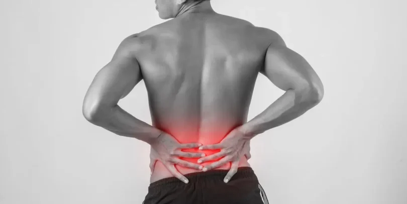 Mann hält sich mit beiden Händen den schmerzenden unteren Rücken – symbolisch für Beschwerden bei einem Bandscheibenvorfall im Lendenbereich.