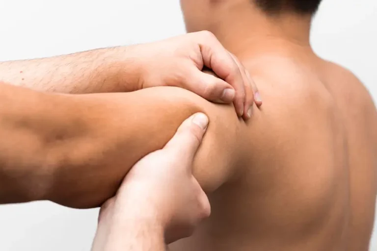 Physiotherapeut behandelt Triggerpunkt im Schulterbereich eines Patienten mit manueller Technik.