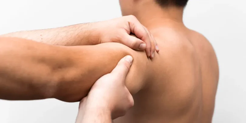 Physiotherapeut behandelt Triggerpunkt im Schulterbereich eines Patienten mit manueller Technik.