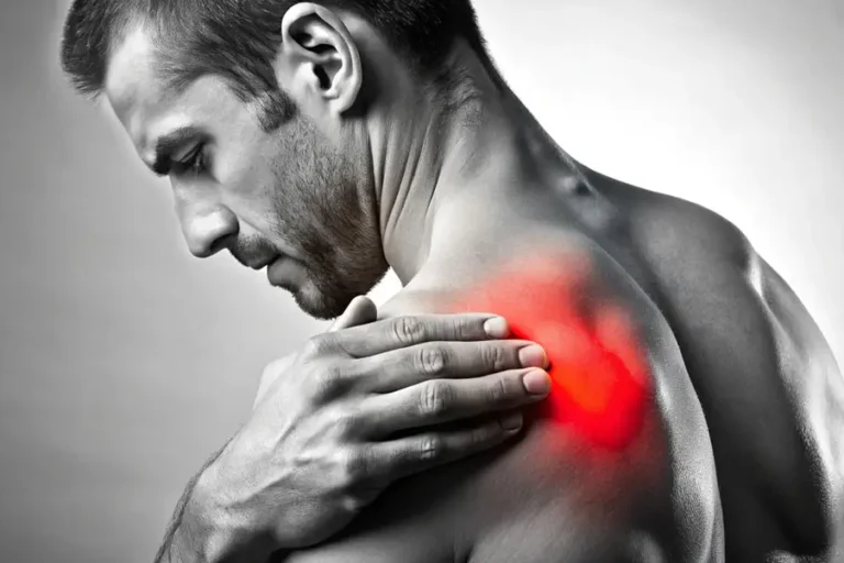 Mann hält sich schmerzhaft die Schulter – rot markierter Bereich weist auf eine Verletzung oder Entzündung im Schultergelenk hin.