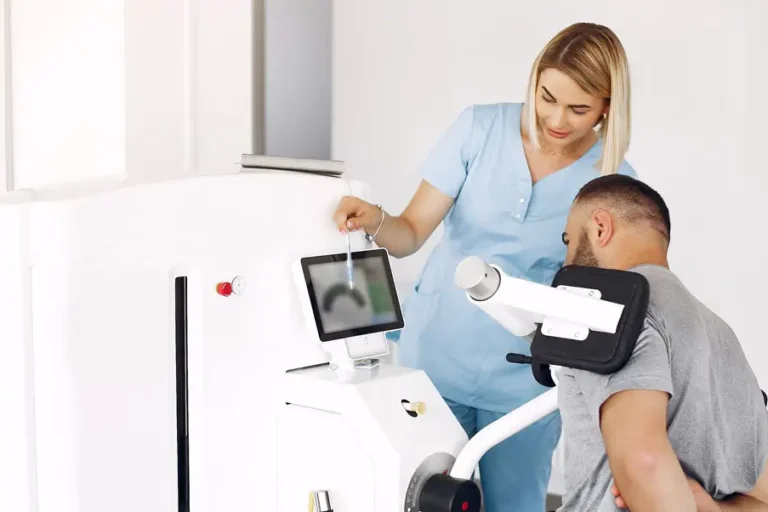 Physiotherapeutin betreut einen Patienten beim Training an einem Reha-Gerät in einer modernen Physiotherapiepraxis.