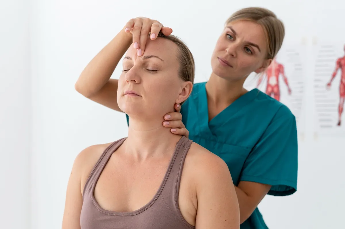 Physiotherapeutin behandelt konzentriert die Halswirbelsäule einer Patientin in einer hellen Praxis.
